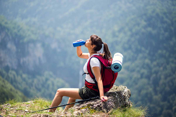 A backpacking woman drinking water on a mountain