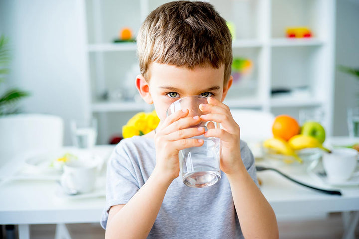 A young boy drinking a glass of water