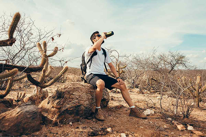 Hiker in a desert drinking from a water bottle